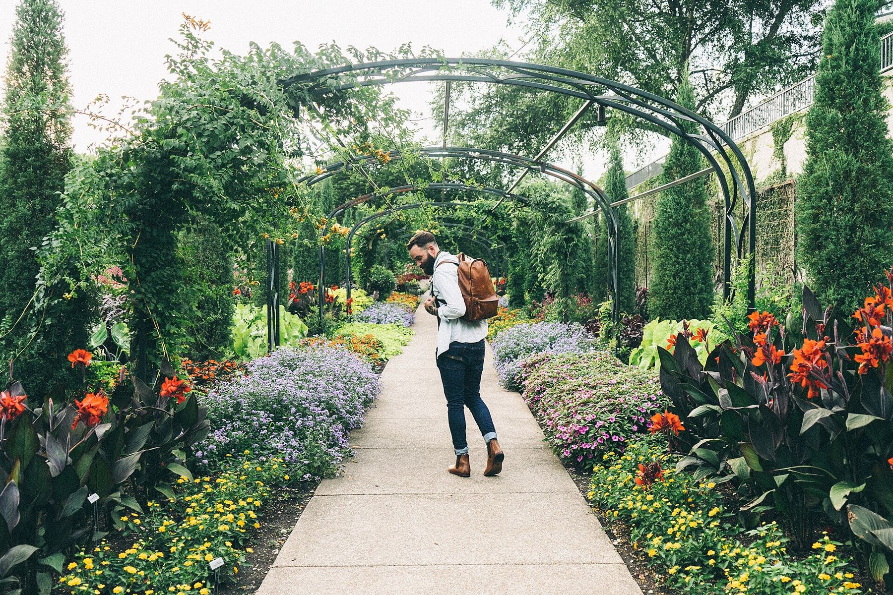 Gepflegter Gartenweg mit bunten Blumenbeeten und Rankbögen